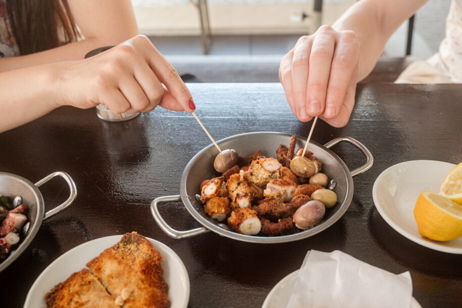 Hands picking fried octopus from Viana do Castelo coast.